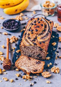 a loaf of banana nut bread on a cutting board next to some nuts and honey