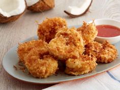 some fried food is on a plate next to coconuts and ketchup sauce