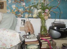 a bed room with a vase filled with flowers on top of a table next to a lamp