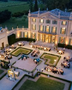 an aerial view of a mansion at night with people sitting in the courtyard and eating