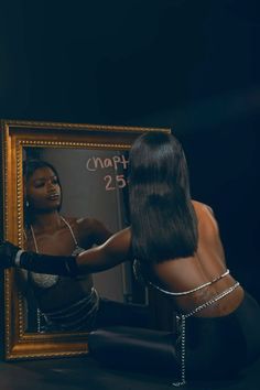 a woman sitting on the ground in front of a mirror with her reflection and writing on it