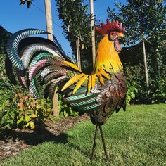 a colorful rooster statue standing in the grass