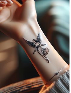 a woman's wrist tattoo with an angel on the back of her left arm