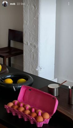 an open carton of eggs sitting on top of a table next to a bowl of lemons