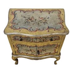 an ornately painted chest with drawers on the top and bottom, against a white background