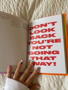 a woman's hand holding an open book with the words don't look back you're not going that way