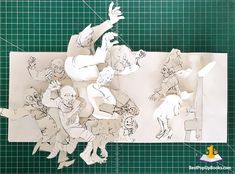 paper cut out of cartoon characters on a green cutting mat with scissors and rulers