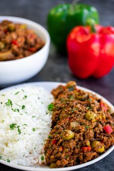 a plate with rice, meat and peppers next to two bowls filled with chilis