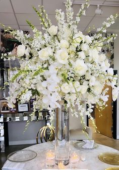 a vase filled with lots of white flowers on top of a table next to candles