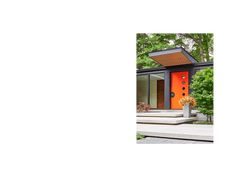 an orange door sits in front of a modern home with steps leading up to it