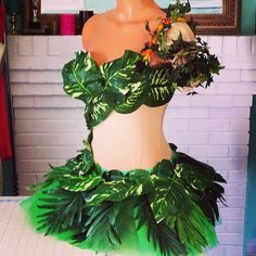 a mannequin is dressed up with green leaves and flowers on it's body