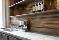 a kitchen counter with bottles of wine on the shelf above it and a sink below