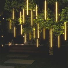 an outdoor area with trees and lights on the wall, in front of a building