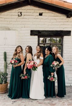 a group of women standing next to each other in front of a white brick building