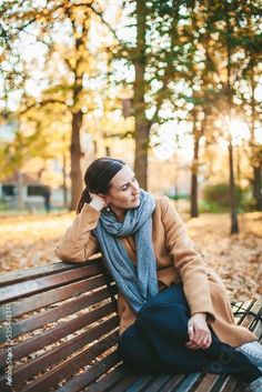 a woman sitting on top of a wooden bench