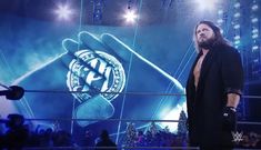 a man standing in front of a large screen with his hand on the wrestling ring