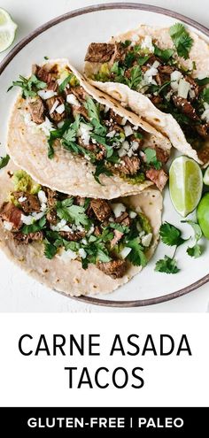 three tacos on a plate with limes and cilantro