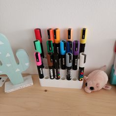 several pens are lined up on a desk next to a stuffed animal