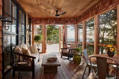 a porch with chairs and tables on the deck overlooking the water is furnished with wood paneling