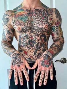 a man with lots of tattoos on his chest and hands is standing in front of a door