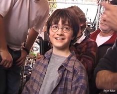 a young boy with glasses sitting in front of a group of people