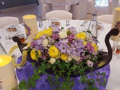 a bouquet of flowers on a table with candles and place settings for the guests to sit at