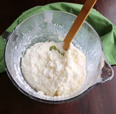 a wooden spoon in a mixing bowl filled with flour and sugar on top of a green napkin