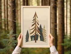 a person holding up a poster with trees on it in front of some pine trees