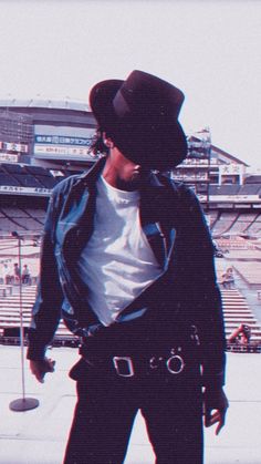 a man wearing a cowboy hat standing in front of a stadium