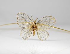 a gold wire butterfly on a white surface