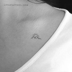 a small sun tattoo on the back of a woman's neck