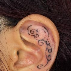 a close up of a person's ear with tattoos on it