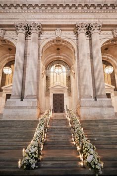 an ornate building with stairs leading up to the door and flowers on the steps in front