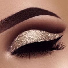 a woman's eye with gold and silver glitters on her eyeshadp