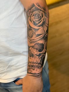 a man with a skull and rose tattoo on his arm