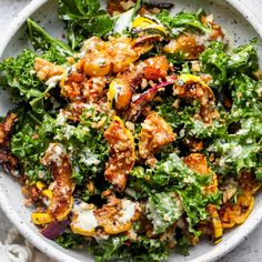 a white bowl filled with salad on top of a marble countertop next to a knife and fork