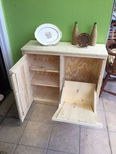 a wooden cabinet sitting on top of a tile floor next to a green painted wall