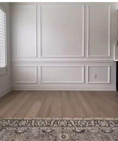 an empty room with white walls and wood floors