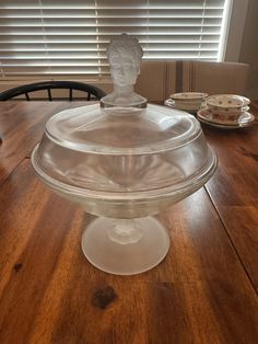 a glass cake dish sitting on top of a wooden table