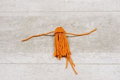 an orange tasseled object on a white wooden surface