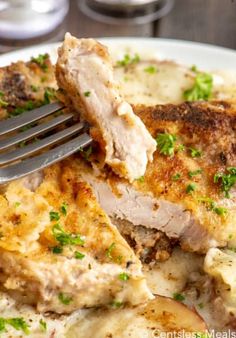 a close up of a plate of food with meat and potatoes on it, with a fork in the middle