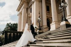 the bride and groom are walking down the stairs together in front of an old building