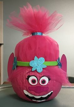 a pink trolly pumpkin with a blue bow on it's head and big eyes