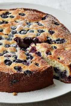 a blueberry cake with one slice cut out and served on a white platter