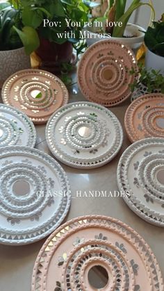 six pink and white plates sitting on top of a table next to potted plants