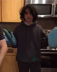 two people standing next to each other in a kitchen with oven mitts on their hands