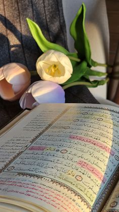 an open book sitting on top of a table next to flowers