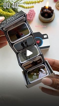 a person holding an open film strip with pictures on it and candles in the background