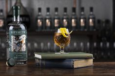 a bottle of whisky next to a glass on top of a book and some books