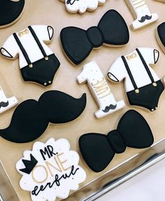 decorated cookies in the shape of mustaches and bow ties are displayed on a tray